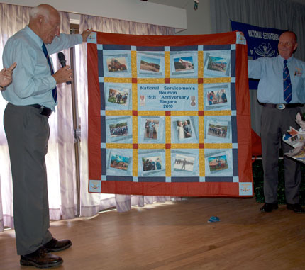 John Curruthers proudly displays his gift, a quilt made by Margaret Elbourne